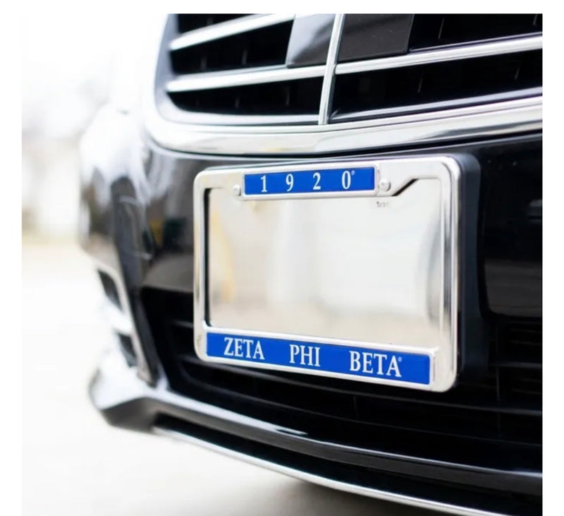 Polished Zeta Phi Beta license plate frame reading 1920 and ZETA PHI BETA in royal blue, mounted on the front of a black car.