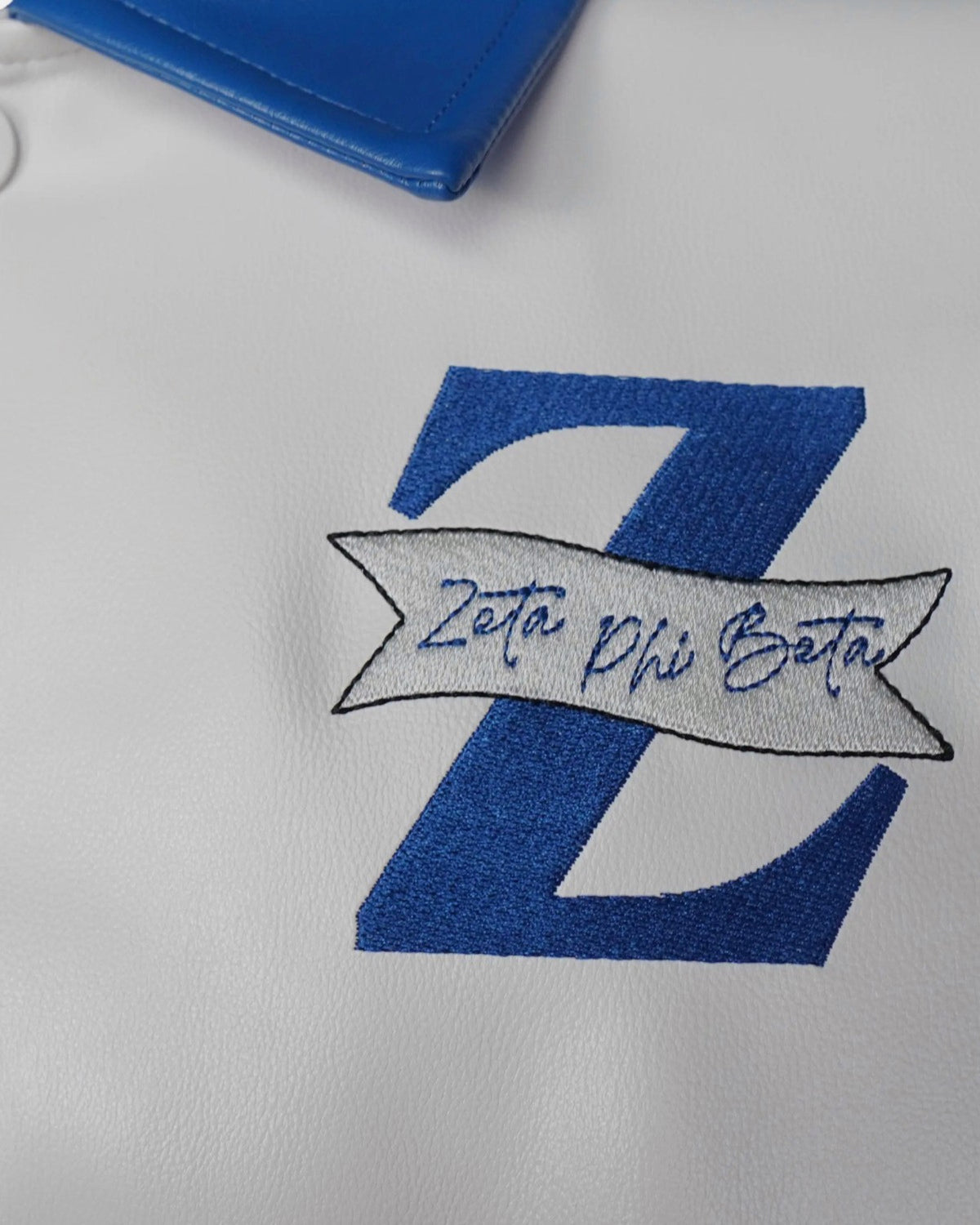 Detail: the Royal Blue Z and Zeta Phi Beta script banner on the white leather chest panel