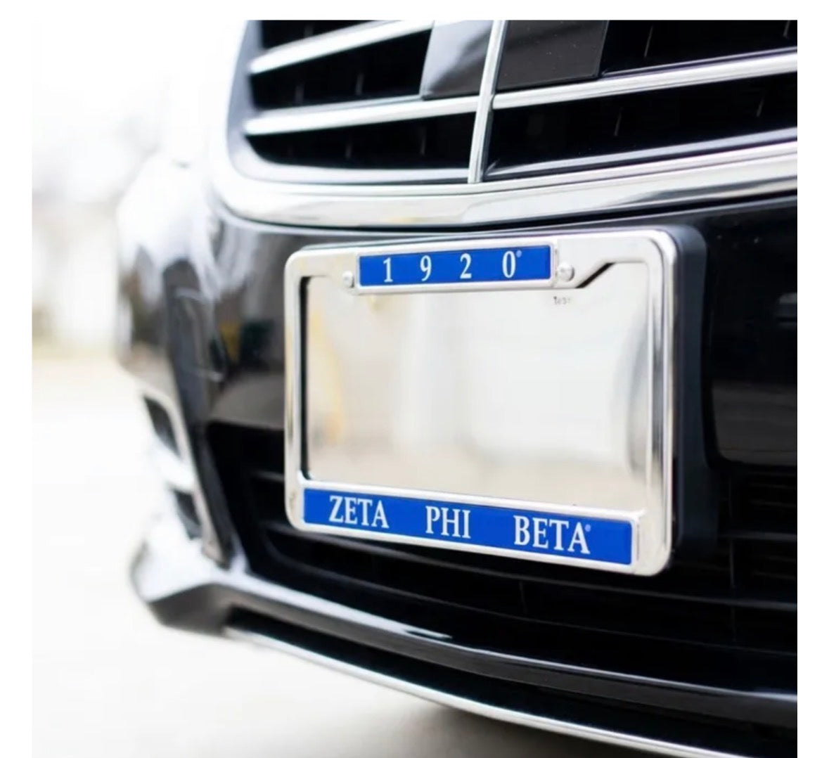 Polished Zeta Phi Beta license plate frame reading 1920 and ZETA PHI BETA in royal blue, mounted on the front of a black car.