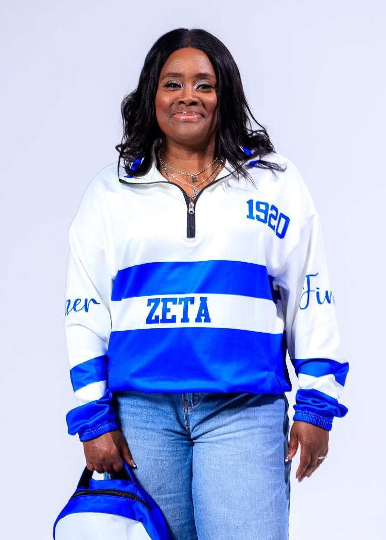Woman wearing a Zeta Phi Beta-themed sweatshirt and holding a matching bag on a white background