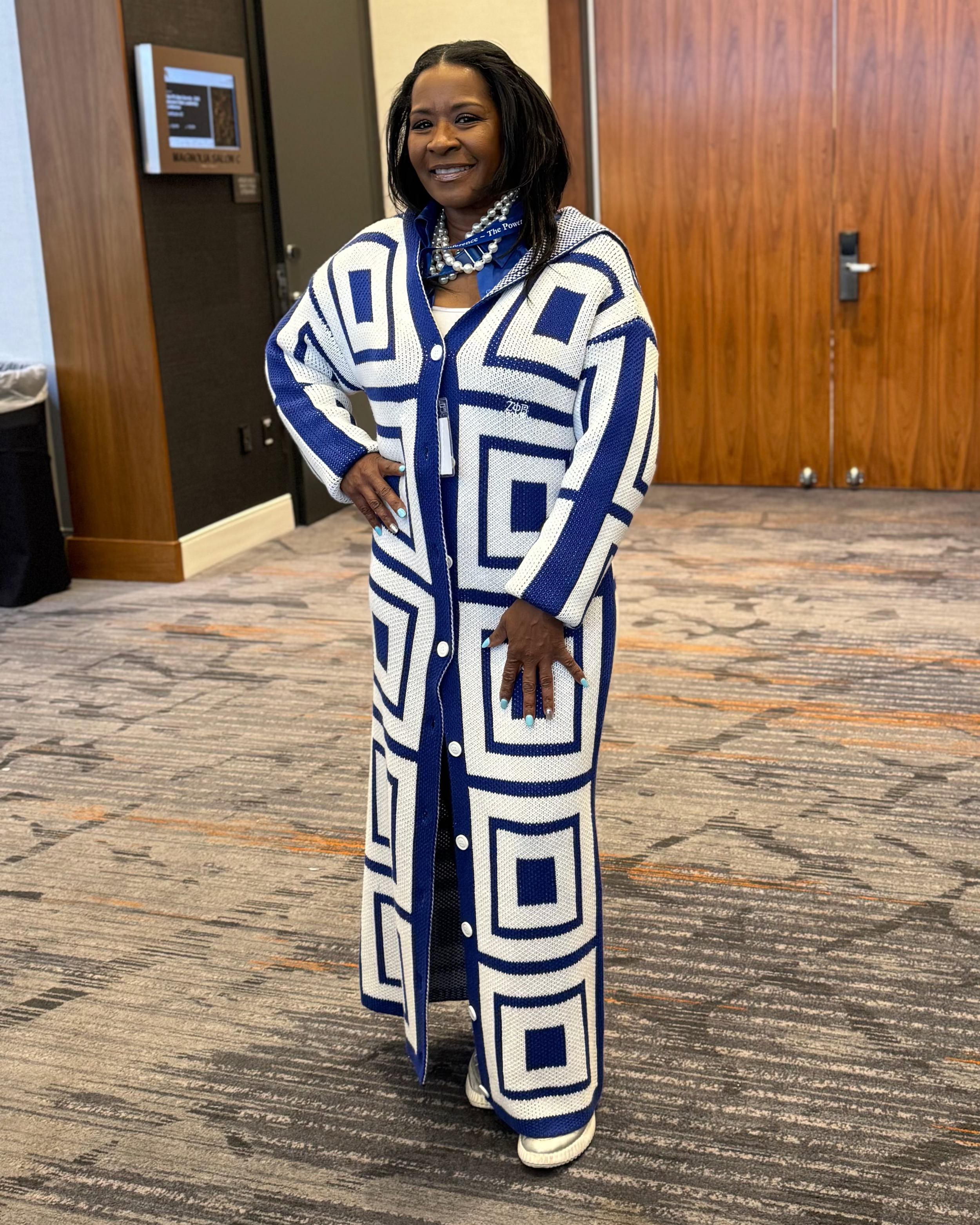Woman wearing a blue and white patterned coat in an indoor setting