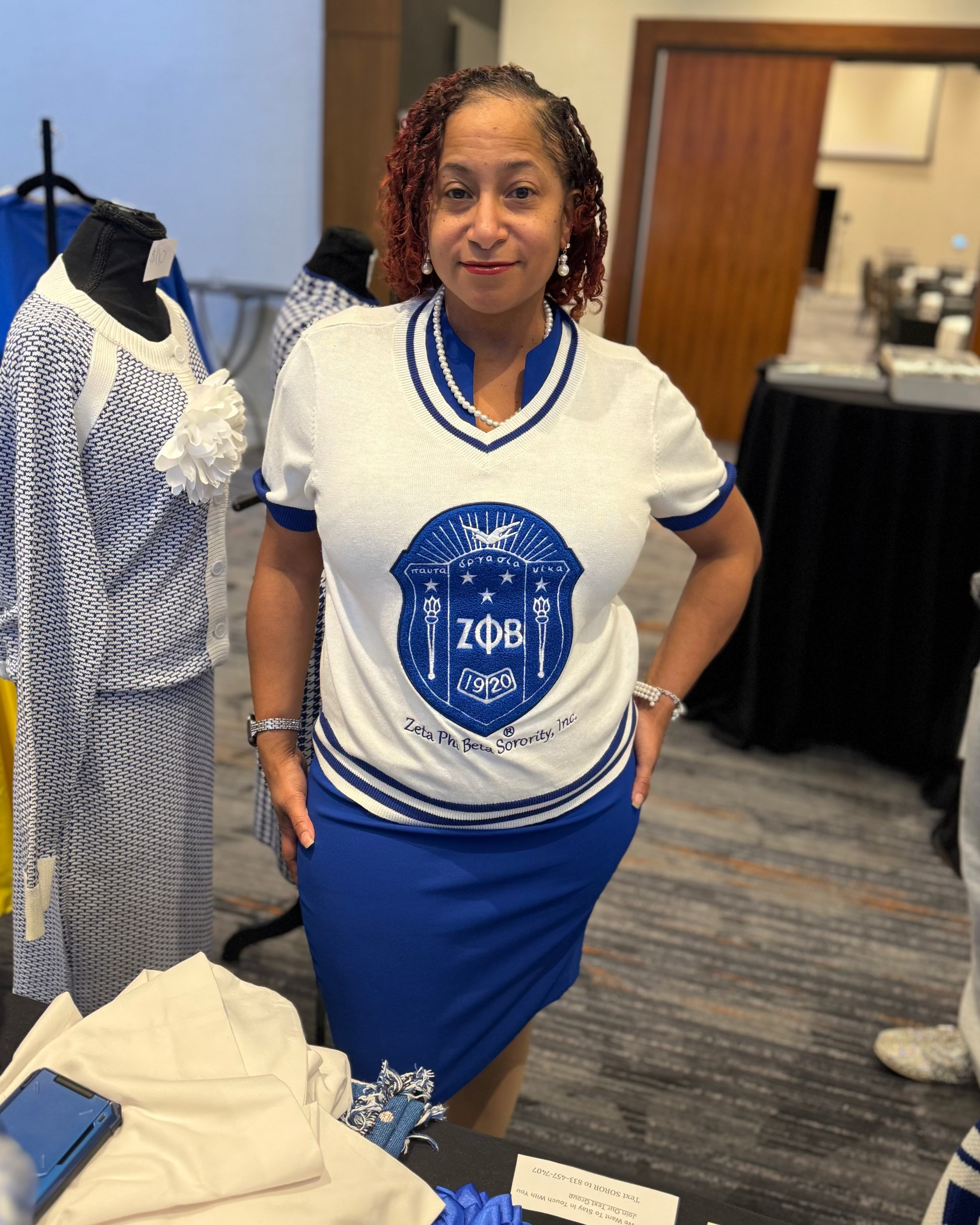 Woman wearing a Zeta Phi Beta sorority shirt in an indoor setting with tables and chairs.